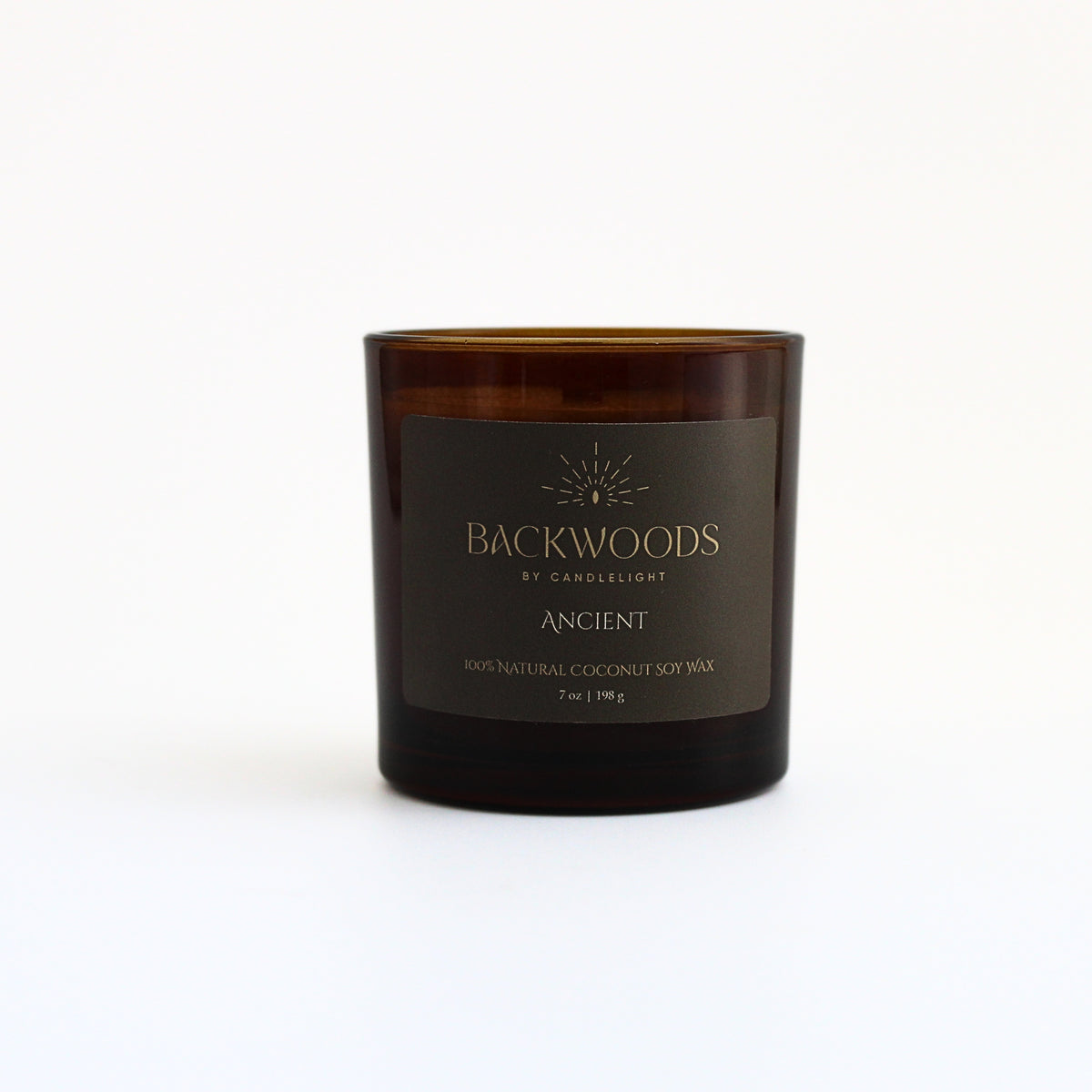 Ancient 7 oz wooden wick candle in an amber glass jar with an olive and gold label, on a white background