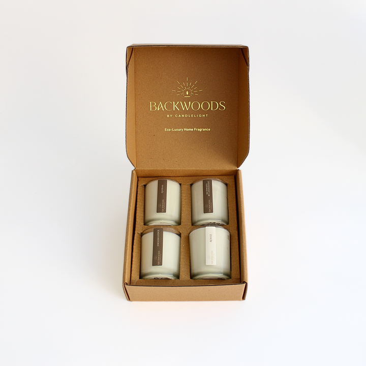 Warm & Cozy Discovery Scent Set opened, with Ashram, Backwoods By Candlelight, English Lodge and Rouge votives in a kraft box printed Eco-Luxury Home Fragrance