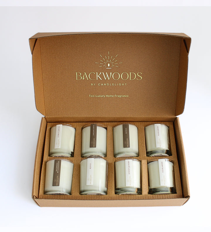 Complete Discovery Scent Set opened, with eight 2.5 oz wooden wick votives in a kraft box printed Eco-Luxury Home Fragrance