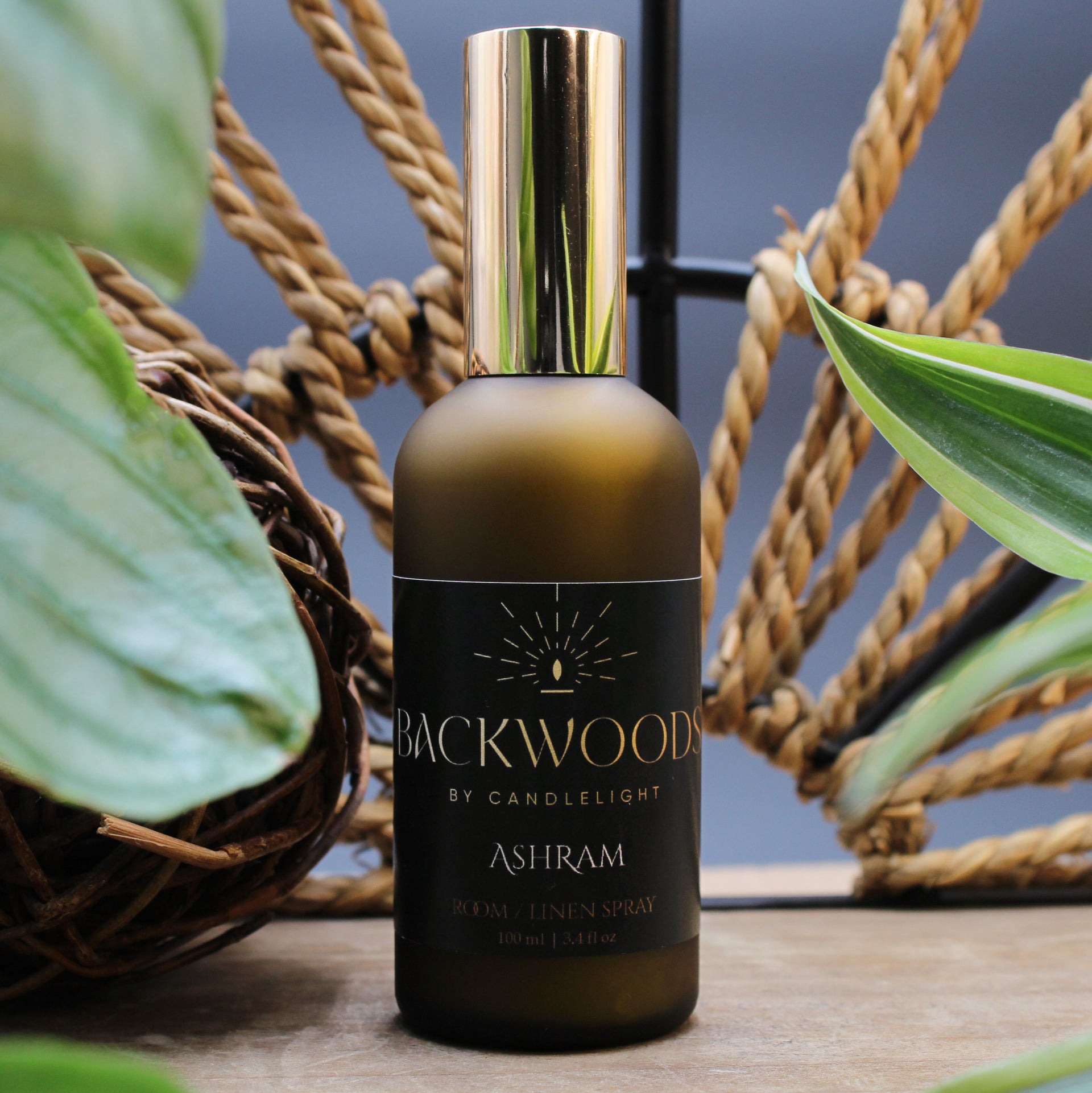 Room & Linen Spray bottle labeled 'Backwoods by Candlelight Ashram' on a white background