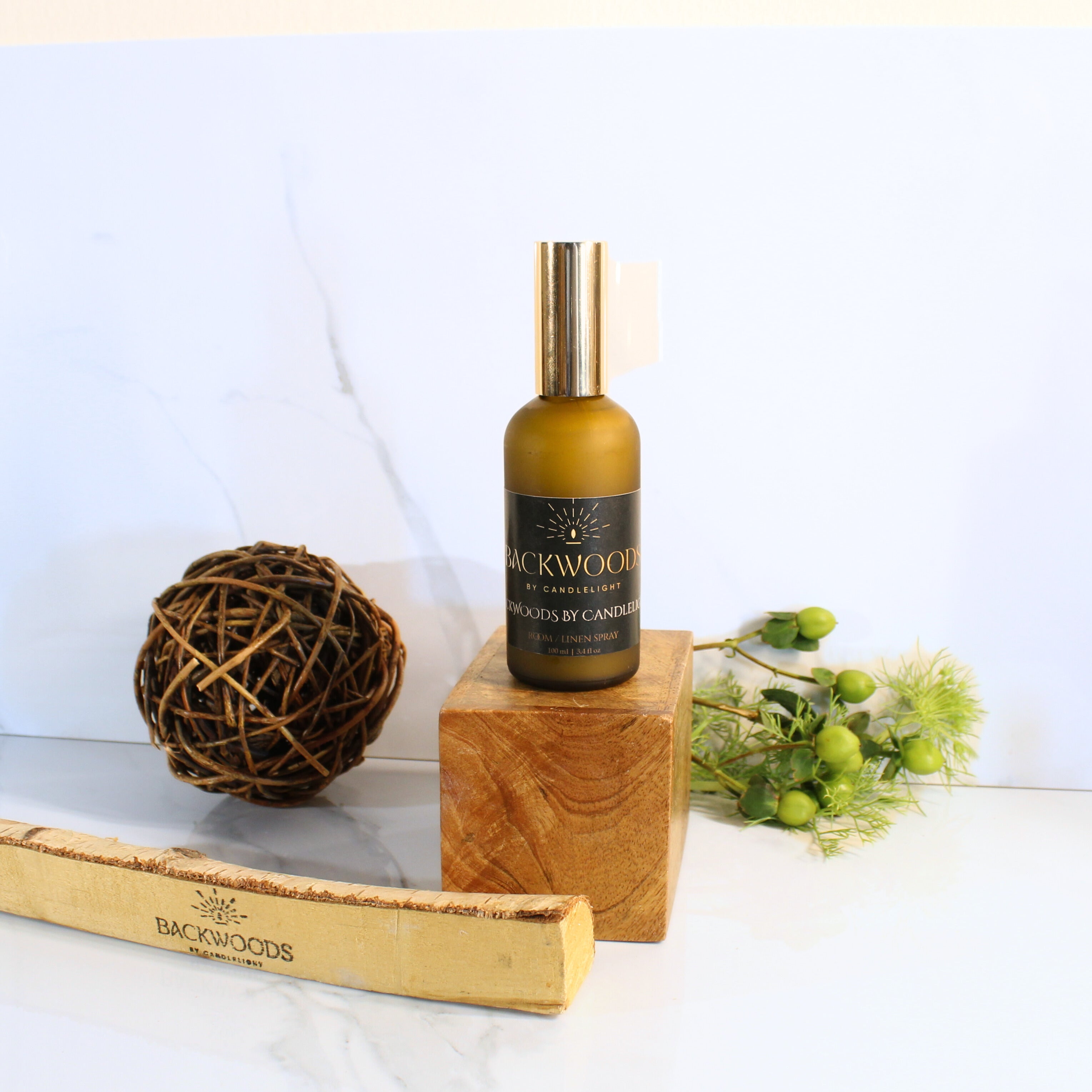Brown spray bottle with gold cap labeled 'Backwoods by Candlelight' on a white 