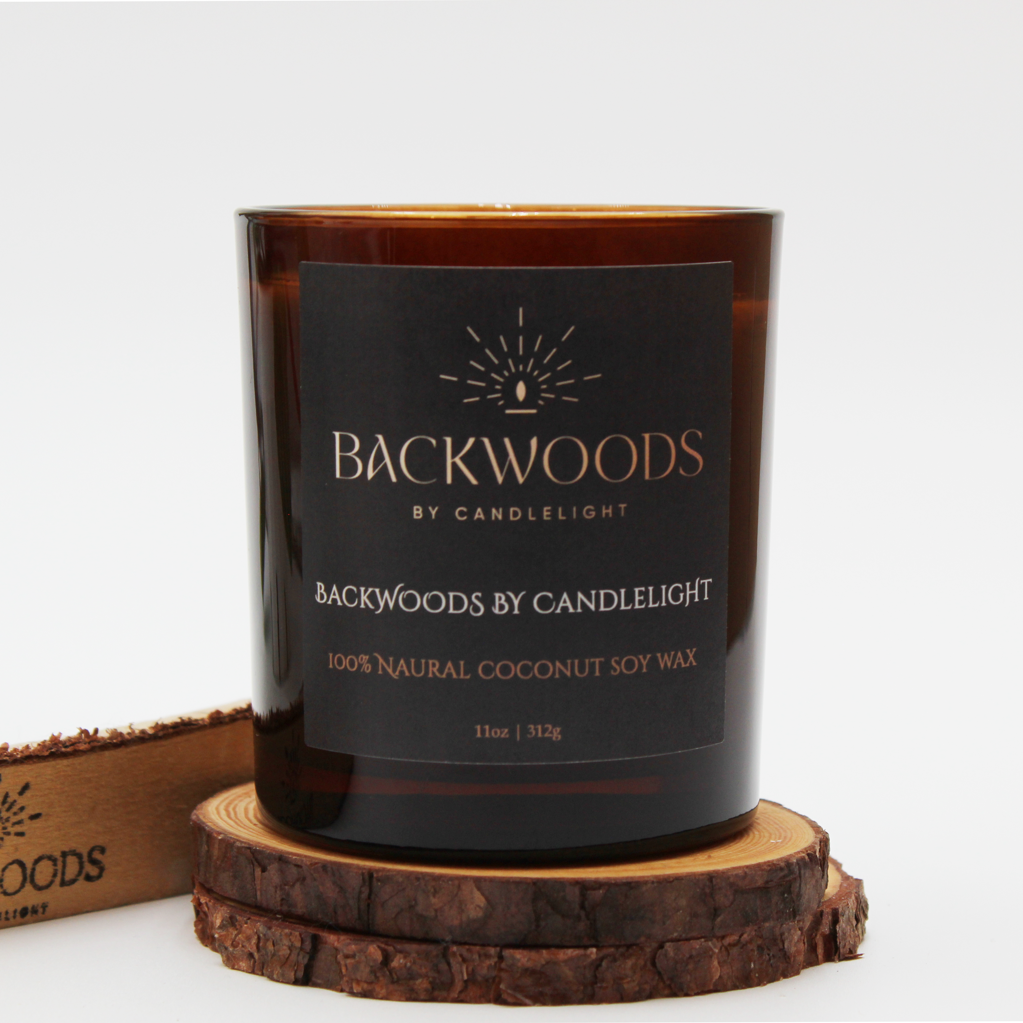 Backwoods By Candlelight non toxic scented candle front label with leaf, wooden wick and candle coaster.
