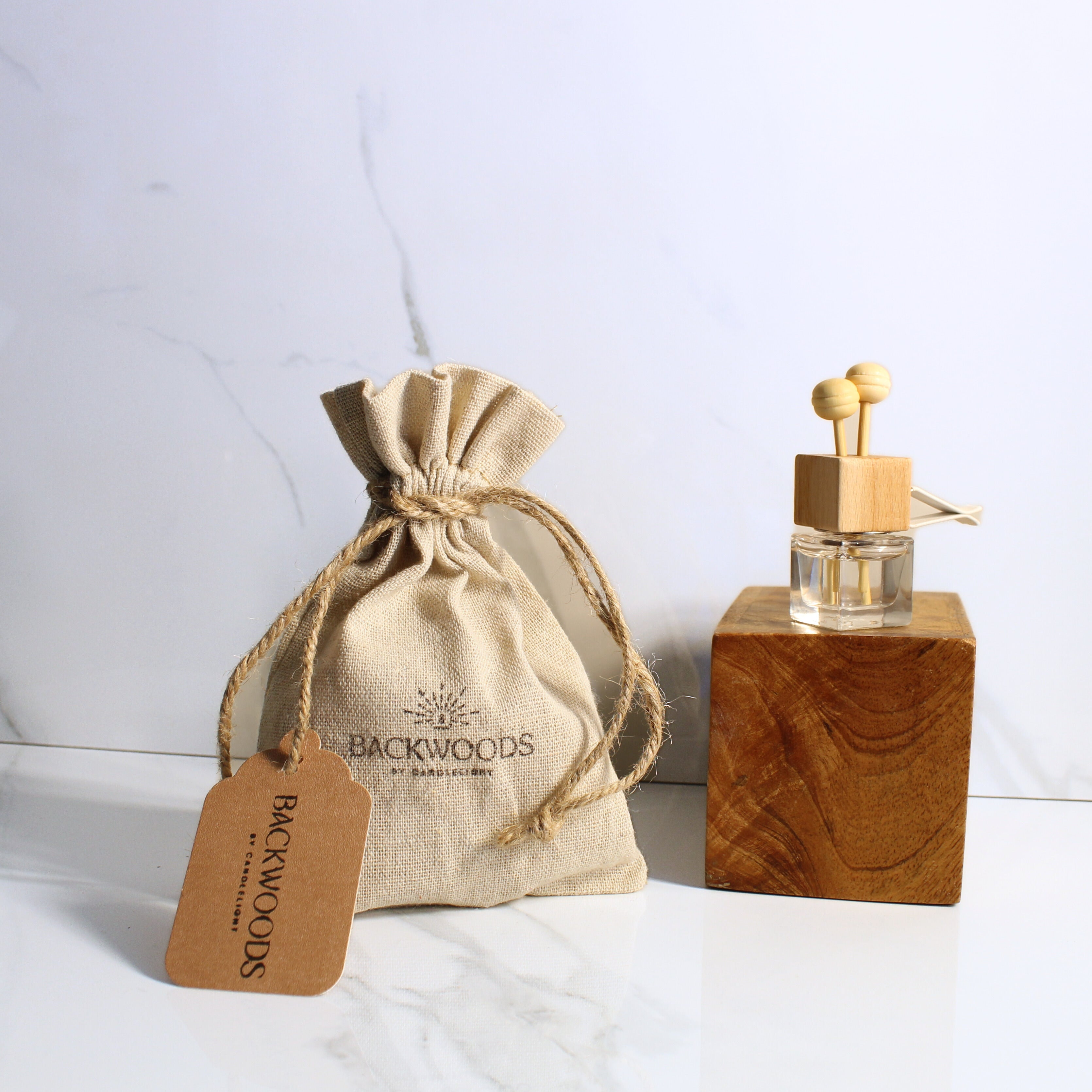 Car Diffuser bottle with wooden design and matching drawstring bag on a light background
