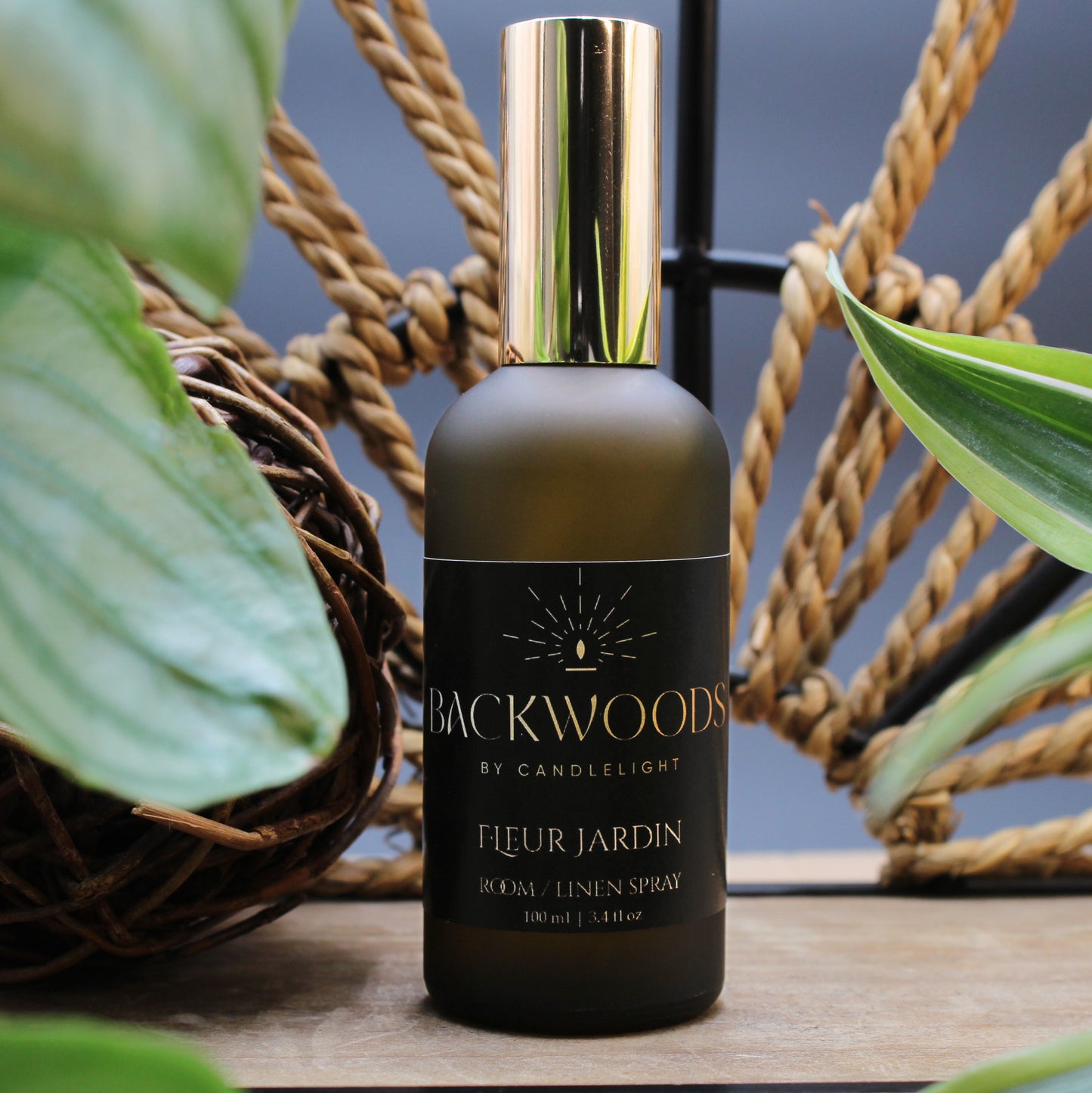 Brown spray bottle with gold cap labeled 'Backwoods by Candlelight Fleur Jardin' on a white background