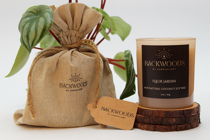 Backwoods By Candlelight all natural candle, non-toxic candle. Fleur Jardin packaging with handmade candle, wooden wick, plant and candle coaster.