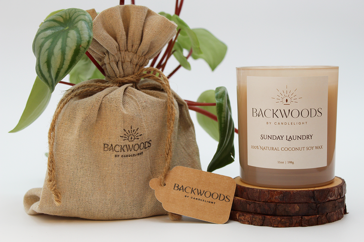 Backwoods By Candlelight all natural candle, non-toxic candle. Sunday Laundry packaging with handmade candle, wooden wick, plant and candle coaster.