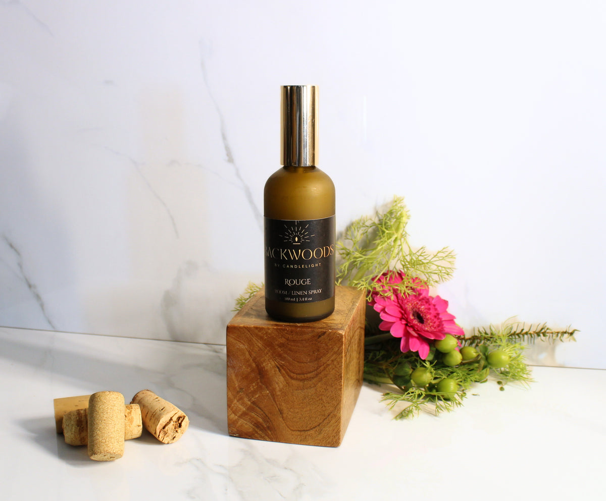 Bottle of Blackwoods perfume on a wooden block with flowers and corks in the background