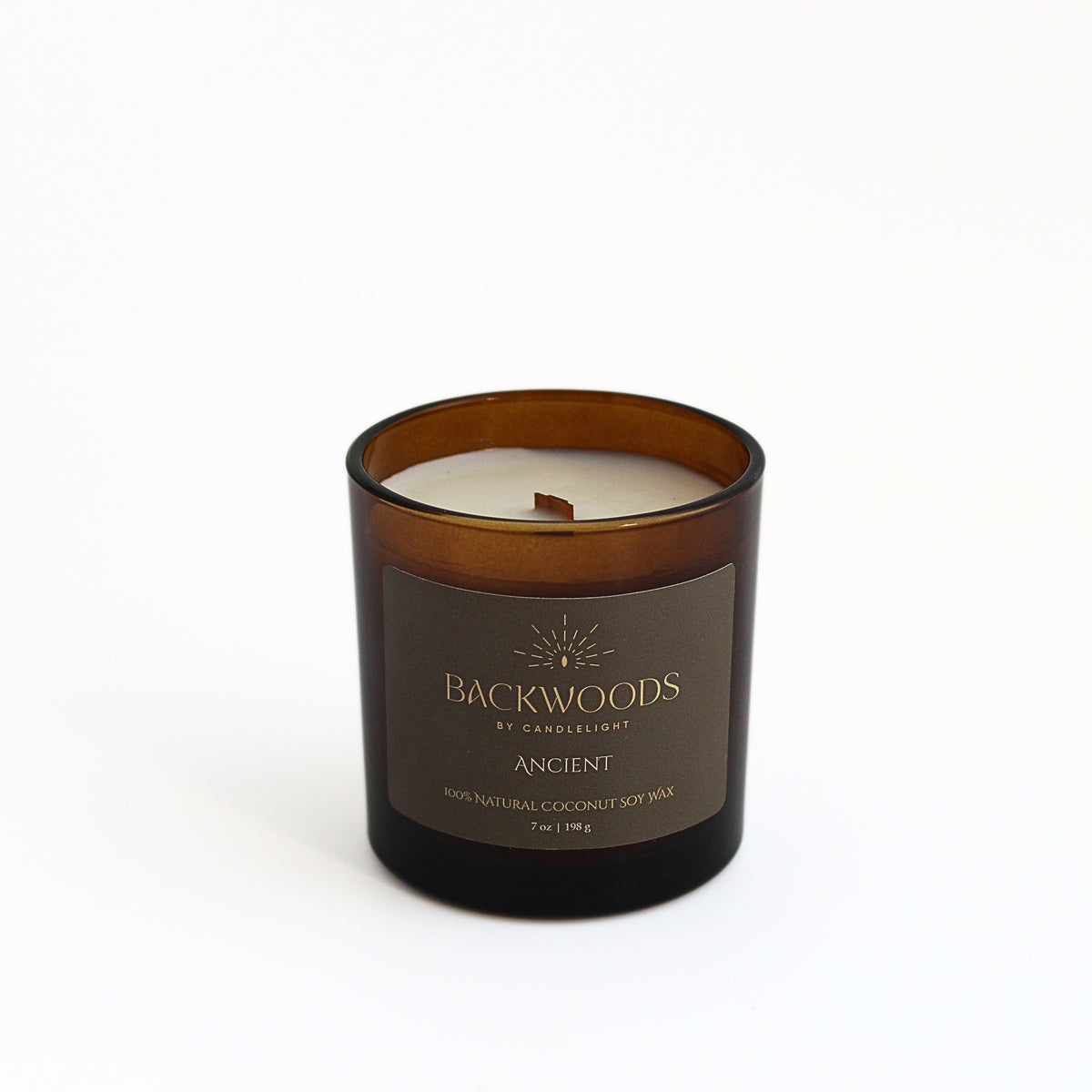 Ancient 7 oz wooden wick candle in an amber glass jar with an olive and gold label, on a white background