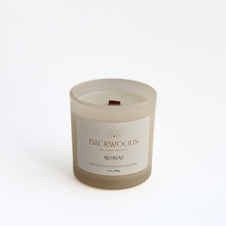 Retreat 7 oz wooden wick candle in a frosted ivory jar with a cream and gold label, on a white background